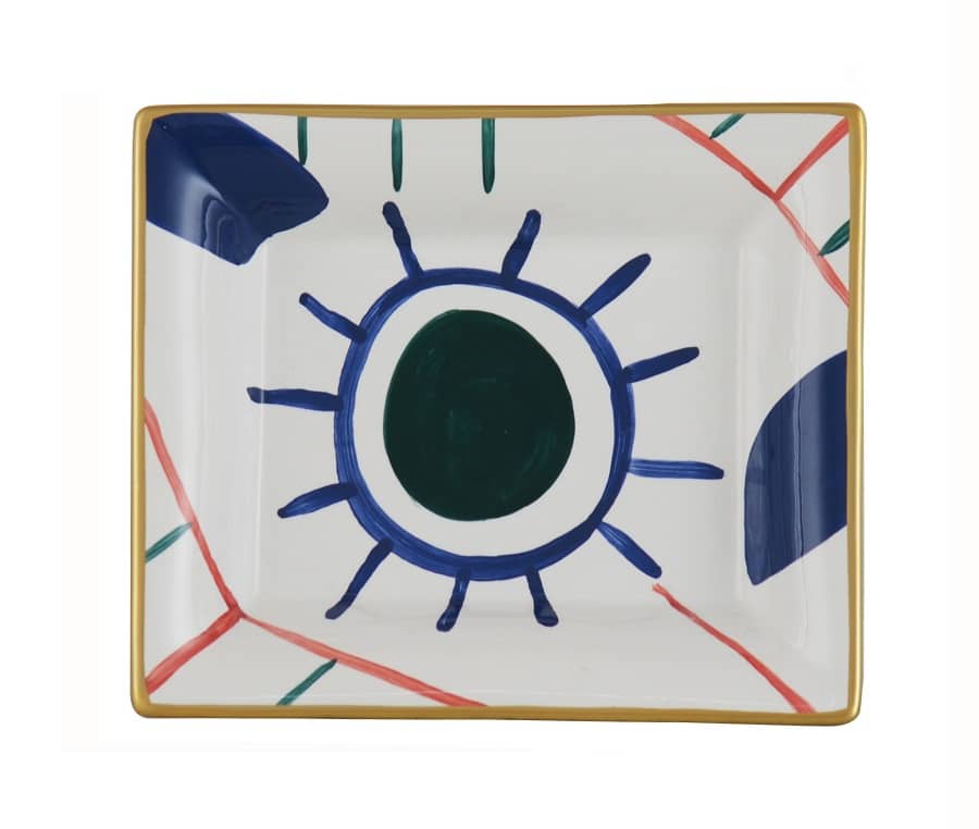 Assiette carrée en céramique blanche décorée d'un motif abstrait œil stylisé bleu et vert, bordure dorée et lignes rouges.