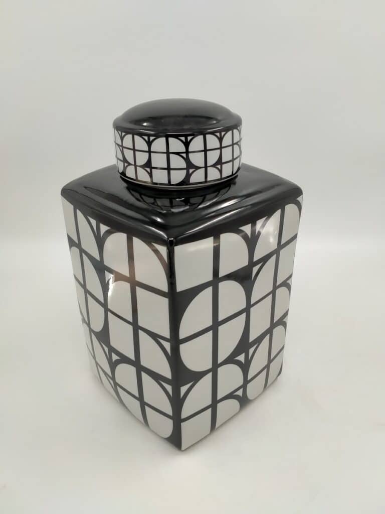 Bocal carré en céramique noir et blanc brillant, orné d'un motif géométrique de cercles coupés par des lignes noires, avec un couvercle assorti.