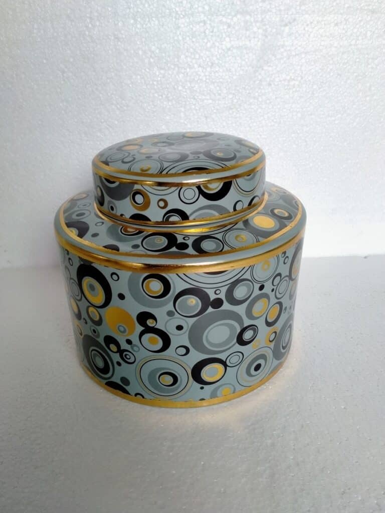 Boîte de conserve décorative à deux niveaux, style rétro, motif cercles gris, jaune et noir, bordures dorées, sur fond blanc texturé.