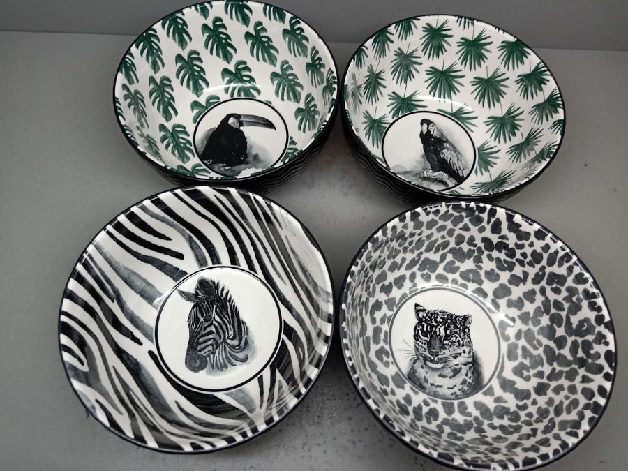Quatre bols de service décoratifs, deux avec motifs jungle (feuilles de monstera et perroquet, toucan) et deux avec motifs animaliers (zèbre et léopard) en noir et blanc.
