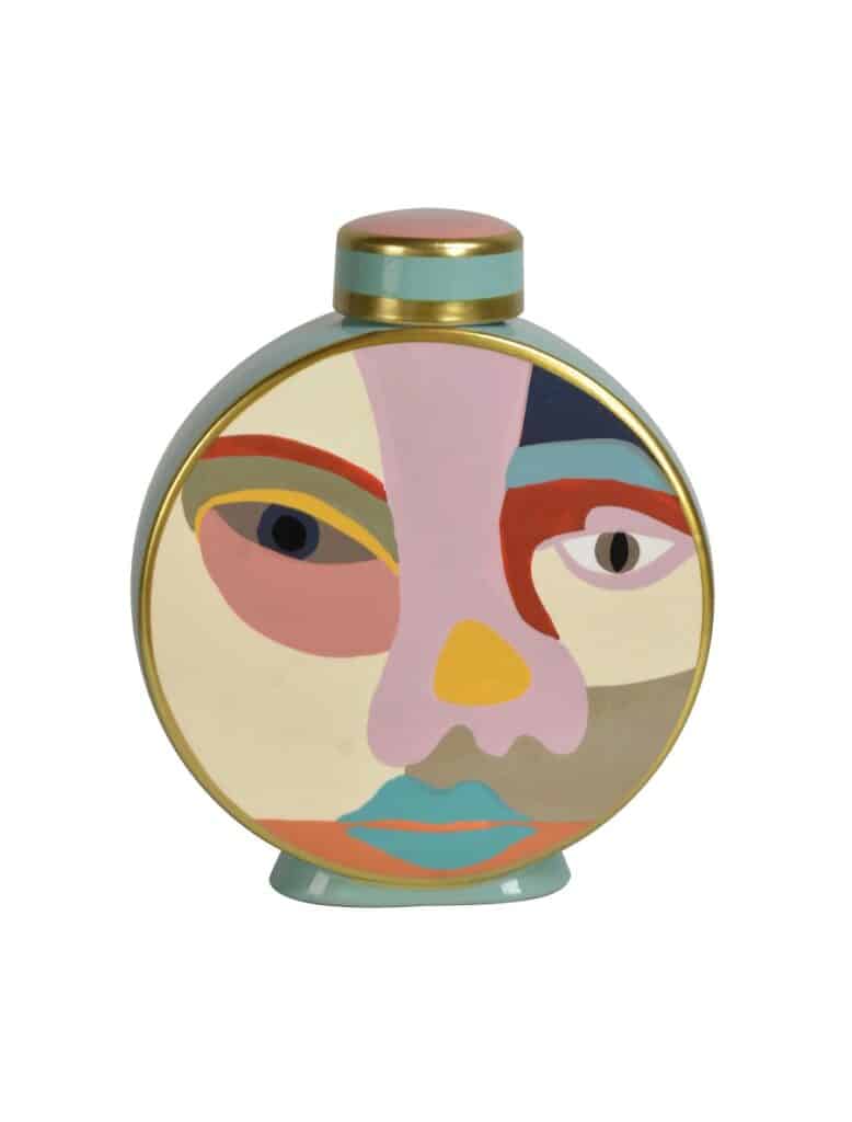 Flacon de parfum décoratif rond, style art abstrait, peint avec un visage aux couleurs vives, bordure dorée et bouchon rose/bleu sarcelle.