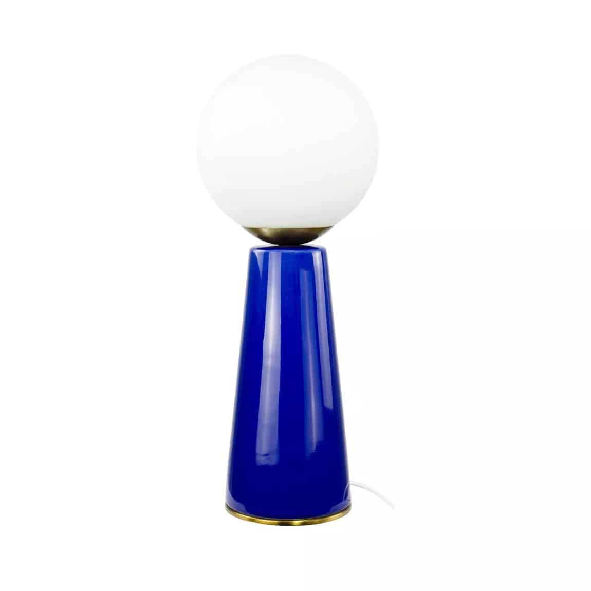 Lampe de table design avec base conique bleu cobalt laqué, surmontée d'un globe lumineux blanc opale et de détails en laiton.